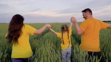 Anne ve babasının tarlada yeşil buğdayla koştuğu küçük bir çocuk, mutlu aile kavramı, kırsal çiftçinin çocuk ve eşiyle eğlenmesi, çiftçilik, takım çalışması, çiftlikte mahsul yetiştirmesi, yavaş çekim.