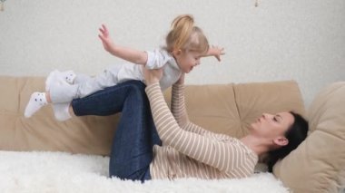 Mutlu, güzel, sağlıklı, sağlıklı bir aile. Küçük, tatlı bir kız çocuğu kaldırıyor. Evdeki kanepede uçuyor.