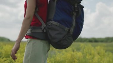 Bir gezgin parktaki kır çiçeklerine dokunur, bin yaşındaki bir kız sırt çantasıyla ormanlık bir alanda seyahat eder, doğada macera aramak için aktif bir turist gezisi