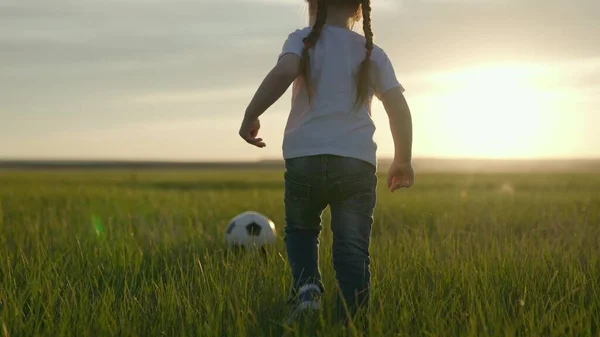 Pequeño niño juega al fútbol con una pelota de fútbol en el campo verde del estadio al atardecer, entrenamiento de equipo de fútbol profesional, entrenamiento activo dinámico para niños, vida de fan, aprender a marcar un gol —  Fotos de Stock