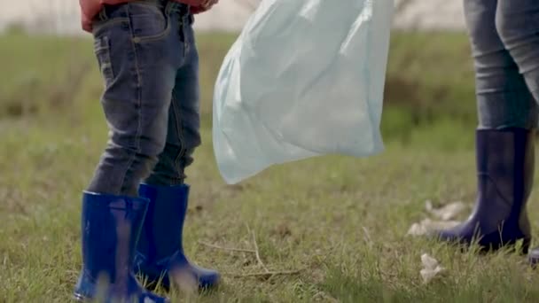 Małe dziecko w zespole wolontariuszy, dziecko sprząta plastikowe śmieci na ziemi, dziewczyna z rodziną sprzątającą naturę przed zanieczyszczeniem, dziecko pomaga światu być czystszym, środowisko, praca zespołowa, szczęśliwa rodzina — Wideo stockowe