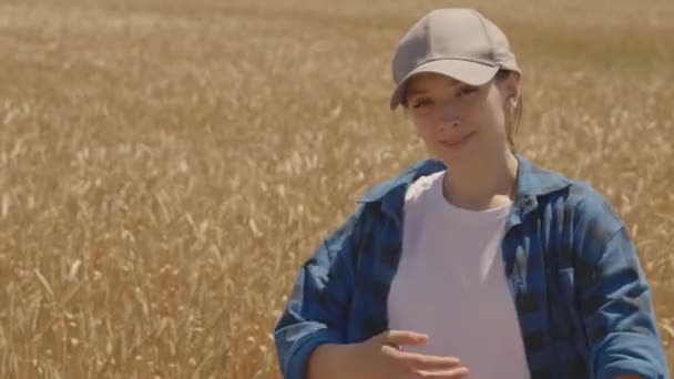 Mutlu çiftçi kız güler buğday tarlasında, tarımda, ekilen çavdar tarlalarında başarılı bir iş, tahıl hasat mevsimi, un ve ekmek üretimi, genç bir tarım uzmanının hayatı — Stok video