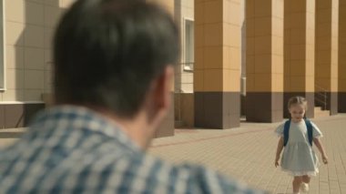 Okul çantalı mutlu kız koşuyor ve sevgili babasına sarılıyor, mutlu aile, çocukluk hayali, küçük çocuklar için anaokulu eğitimi, çocuklar hakkında iyi bilgi, gelişim yetenekleri, okul bahçesi öğrencisi.