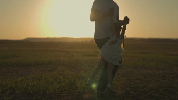 Padre feliz rodeando a un niño pequeño al atardecer, silueta de papá e hija, familia feliz, sueño de la infancia, quiere aprender a volar, jugar al aire libre, fantasía alegre para subir al cielo, día libre — Vídeos de Stock