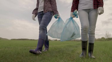 Gönüllüler çöp torbalarında çöp topluyor, doğayı kirlilikten koruyor, atık imhası kollektif takım çalışması, aktivistlerin hayır işleri, temiz doğa, eko, lastik çizmeli insanlar.