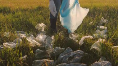 Adam çöp torbasında çöp toplar, yeşil gezegeni temizlemeye gönüllü olur, iyi işler yapar, eko, genç çevreyi korur, koruyucu lastik eldivenler, plastik şişe koleksiyonu yapar.