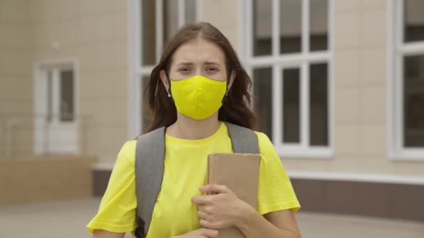 Young girl with textbook in her hands, university student smiling in mask, high school student with book, education of modern society, time pass exams, coronavirus pandemic, covid 19, protect breath — Stock Video