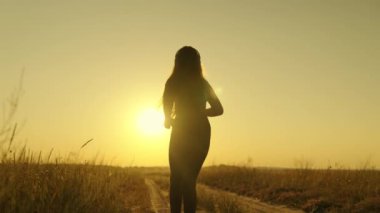 Mutlu kız gün batımında hayaliyle buluşmak için koşar, şafak vakti spor yapar, aktif bir sabah koşusunda müzik dinler, güneş ışığı altında koşar, sağlığına dikkat eder ve formuna dikkat eder, insan figürü.