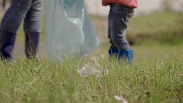 Klein meisje verzamelt plastic afval in de straat in het groene gras, gelukkig gezin, kinderen helpen volwassenen in het schoonmaken van land, kind werk in vrijwilliger team te verzamelen afgedankte vuilnisbelt, milieu, eco — Stockvideo