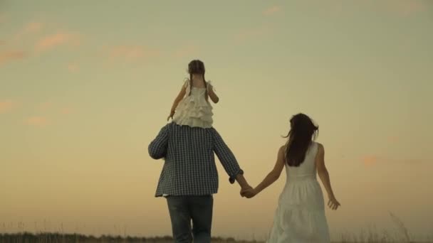 Gelukkig gezin, vrolijke moeder, vader en kind lopen zonsondergang, kleine jongen rijdt vader schouders, moeder spelen met baby voor wandeling, leven met ouders, lopen lachen mensen tegen de achtergrond van de avond hemel — Stockvideo