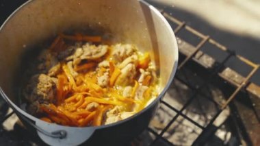 Havuçlu et ve karabiber doğada bir tencerede kaynatılır, tava protein çorbası, turist eğlencesi, ateşte yemek ve mutlu bir aile yemeği ile buharlaşıp köpürür.