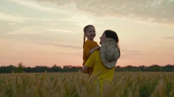 Une bonne agricultrice mère avec un enfant dans un champ avec du blé au coucher du soleil, cultivant du grain pour faire du pain, un enfant heureux, une entreprise familiale dans un ranch, examinant les cultures cultivées avec un bébé dans ses bras — Video