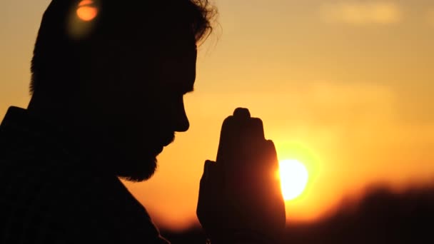 Un hombre rezando con las manos al atardecer, una silueta de un hombre pidiendo ayuda y perdón desde el cielo, días felices de romadán, soñando con un milagro, meditando en el resplandor del sol al aire libre — Vídeo de stock