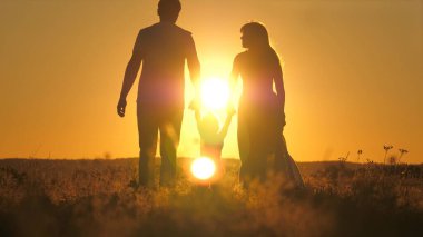 Küçük bir çocuk anne ve babasıyla gökyüzünde parlak bir günbatımında yürür. Seyahat ederken ailenle gün doğumunu karşıla. Annen ve babanla yürüyüşe çık. Çocuk ve sevgi dolu ebeveynler parkta yürürler.