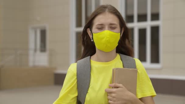 Jonge meisje schoolmeisje glimlachen in een beschermend masker, coronavirus pandemie, covid 19, veilig lopen door de stad, helpt tegen infecties en stof, luchtfiltratie, houden gezonde mensen veilig, concept — Stockvideo