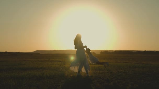 Moeder cirkelt rond in de lucht van het kleine kind bij zonsondergang, het kind speelt met zijn moeder in het zonlicht, wil boven de grond vliegen, kinderdroom, gelukkig gezinsleven, ouder reist met baby — Stockvideo