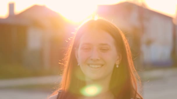 Jovem menina feliz caminha pela rua sorrindo ao pôr do sol na cidade, ficar satisfeito com a vida, mulher livre caminha no parque, andando, câmera lenta, estudante vai estudar ao amanhecer no instituto — Vídeo de Stock