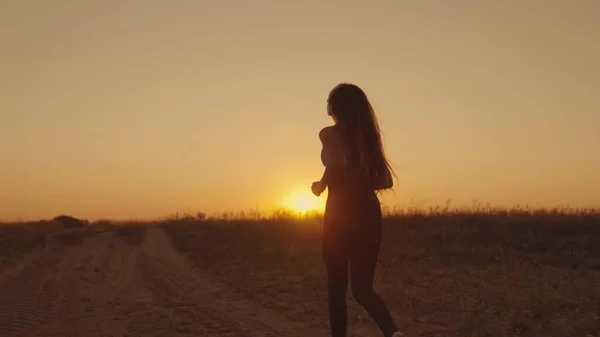 Silhouette of sportive girl runs at sunset in sky outdoors, maintain healthy lifestyle with cardio workouts in sun, female fitness at dawn, morning endurance training against laziness, slow motion. — Stock Photo, Image