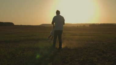 Bir adam gün batımında küçük bir kızı kollarına alır, mutlu bir aile, çocukluk hayali güneşte uçmak, babalar günü, doğada bir çocukla oynamak, gezide neşeli bir ruh hali, babasıyla şafakta buluşan bir çocuk.