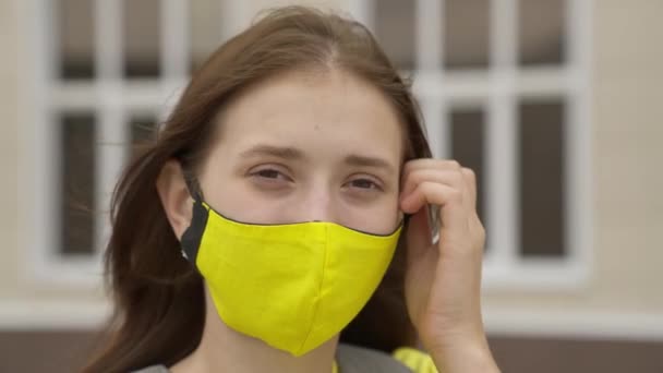 An adult schoolgirl puts on a face mask and smiles, pandemic 2022, filter air for the respiratory tract of the lungs, prevent COVID-19 infection, protect a person from coronavirus with a mask mode — Stock Video