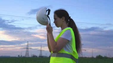 Bir elektrikçi kafasına koruyucu bir kask, kablolarda voltaj altında bir elektrik santrali, mühendislik çalışmalarının enerjisi, elektrik akımı teknolojisi, elektrik işi konsepti koyar.