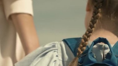Anne küçük bir çocuğu ilkokulun birinci sınıfına götürüyor, okul çantası bir kızın omuzlarında, mutlu bir aile, okul bahçesinde acele bir ders, sırt çantalı bir çocuk eğitim alacak.