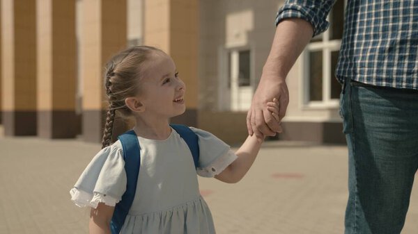 Dad leads the child by hand to school, close-up, a little schoolgirl with backpack, a happy family, a kids childhood dream, an active student girl, good modern education, love and receive knowledge