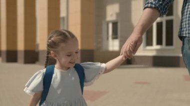 Baba çocuğu elden okula götürüyor, yakın plan, sırt çantalı küçük bir okul kızı, mutlu bir aile, çocukluk hayali, aktif bir öğrenci kız, iyi bir modern eğitim, sevgi ve bilgi.