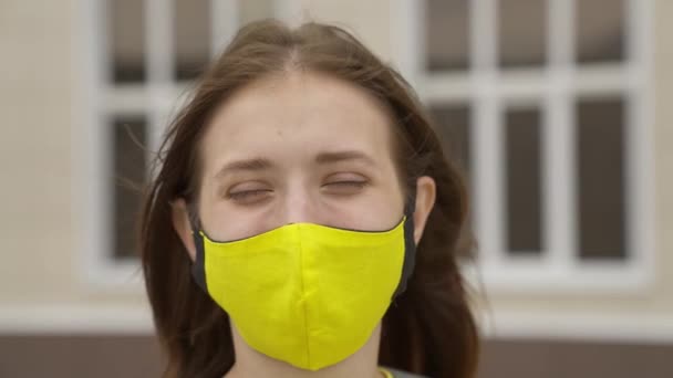 Uma estudante adulta coloca uma máscara facial e sorri, pandemia 2022, filtrar o ar para o trato respiratório dos pulmões, prevenir a infecção COVID-19, proteger uma pessoa do coronavírus com um modo de máscara — Vídeo de Stock