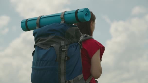 Meisje reiziger met een rugzak op de achtergrond van de lucht, lange afstand wandelen, actieve persoon in het weekend, gebruik het leven tijd, wandelen alleen, ontspannen in de natuur, in harmonie met jezelf — Stockvideo