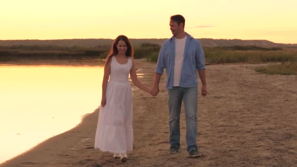 En man och en kvinna går längs stranden vid solnedgången på himlen, romantisk relation mellan två personer, lycklig familj, glada människor gillar att kommunicera, tillbringa en bekymmerslös helg tillsammans — Stockvideo