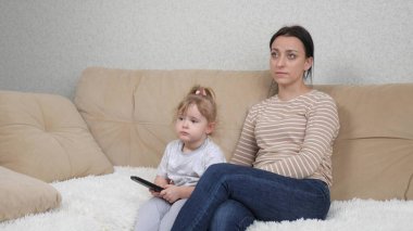 Kanaldaki yayını uzaktan kumandayla değiştir, televizyonu kontrol et, medyada kötü haberleri bul, anne ve küçük bir kız haberleri izlesin, gerçeği öğrendiklerinde üzül...