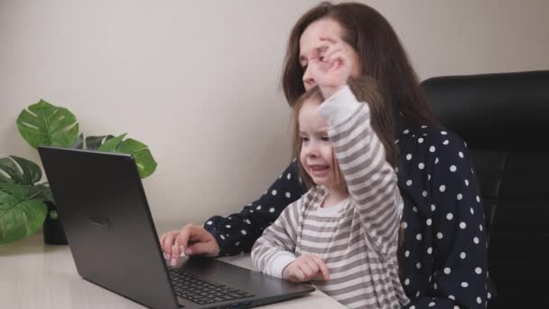 Joven mujer de negocios trabaja en una oficina en casa con un ordenador portátil con un niño en sus brazos, un autónomo en una computadora en el trabajo remoto en cuarentena con un niño, el concepto de una familia feliz, un niño — Vídeo de stock
