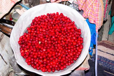 Büyük bir alüminyum kasede taze kirazlar.