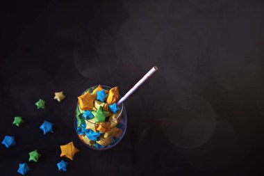 Siyah arka planda kağıt kamış ve renkli origami yıldızlı cam kadehler. Çevre dostu dekor ve tatil konsepti.