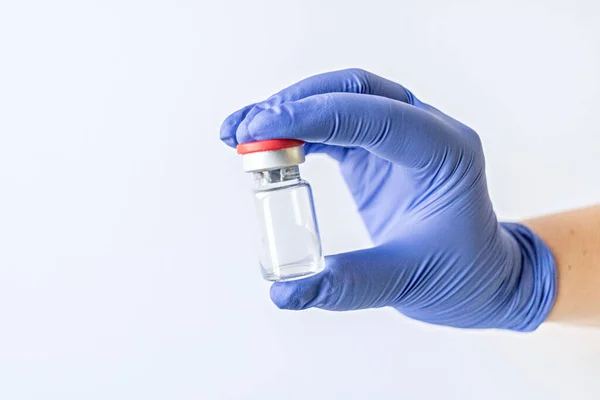 Mavi eldivenli bir doktor bir şişe koronavirüs aşısı tutuyor. Salgın konsepti