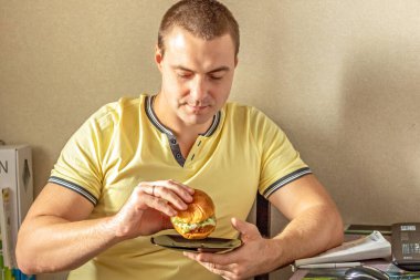 Hamburger yiyen genç ve aç bir adam. Adam fast food yiyor, sağlıksız yemekler. Diyet kavramı