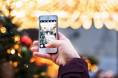 Kız akıllı telefon kamerasıyla yılbaşı ışıklarını fotoğraflıyor.