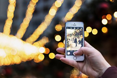 Kız akıllı telefon kamerasıyla yılbaşı ışıklarını fotoğraflıyor.