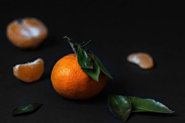 Siyah arka planda yeşil yapraklı taze Mandarin meyvesi.