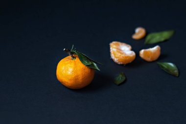 Siyah arka planda yeşil yapraklı taze Mandarin meyvesi.