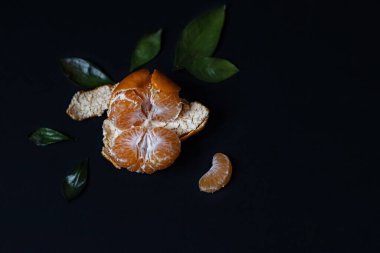 Siyah arka planda yeşil yapraklı taze Mandarin meyvesi.