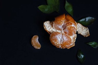 Siyah arka planda yeşil yapraklı taze Mandarin meyvesi.