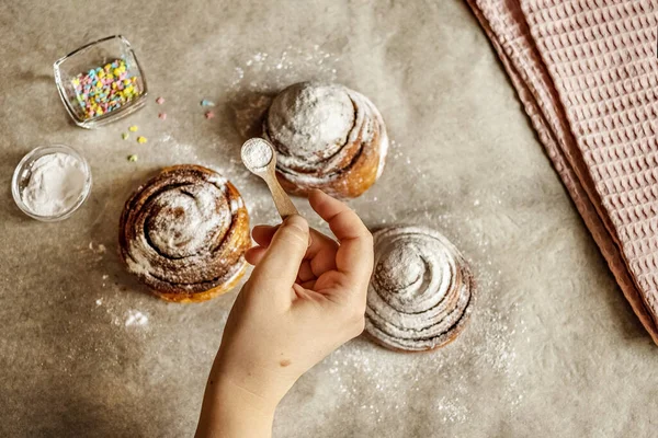 Woman Hand Sprinkles Icing Sugar Fresh Baked Cinnamon Buns — Stock Photo, Image