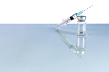 Coronavirus aşısı ile şırınga ve şişe, mavi arka planda enjeksiyon şişesi. Önleme, tıbbi konsept, covid-19 aşılama
