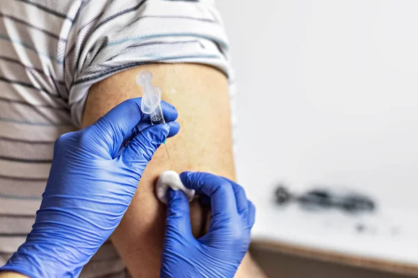 Bir doktor, klinikte bir adamı koronavirüse karşı aşılıyor. Yakın plan. Covid-19 'a karşı aşı, aşı, aşı, önleme kavramı