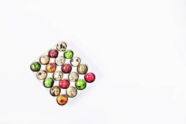 Beyaz arka plandaki bir kutuda renkli bıldırcın yumurtaları. Paskalya tatili konsepti.