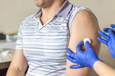 Bir doktor, klinikte bir adamı koronavirüse karşı aşılıyor. Yakın plan. Covid-19 'a karşı aşı, aşı, aşı, önleme kavramı