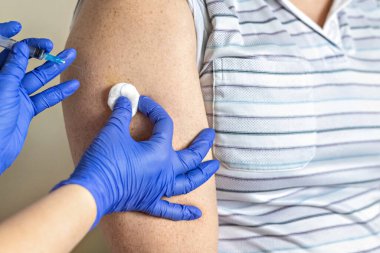 Bir doktor, klinikte bir adamı koronavirüse karşı aşılıyor. Yakın plan. Covid-19 'a karşı aşı, aşı, aşı, önleme kavramı