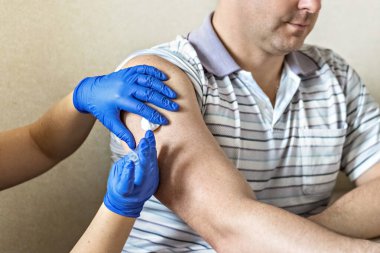 Bir doktor, klinikte bir adamı koronavirüse karşı aşılıyor. Yakın plan. Covid-19 'a karşı aşı, aşı, aşı, önleme kavramı